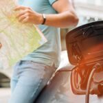 man-charging-electric-car-while-planning-travel-route-with-map