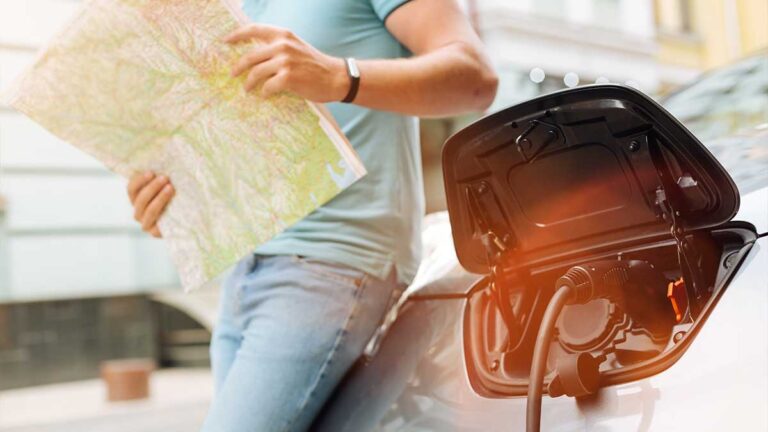 man-charging-electric-car-while-planning-travel-route-with-map