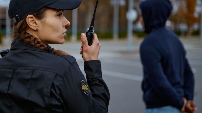 female-bryant-security-guard-using-mobile-radio-while-standing-next-to-perpetrator-in-han