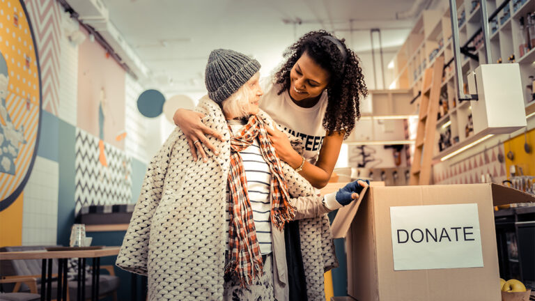 revive-and-restore-volunteer-helping-a-homeless-elderly-woman-pick-out-clothes-from-clothes-drive-box