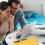 Young couple reviewing life insurance and annuity options online while planning their financial future at home.